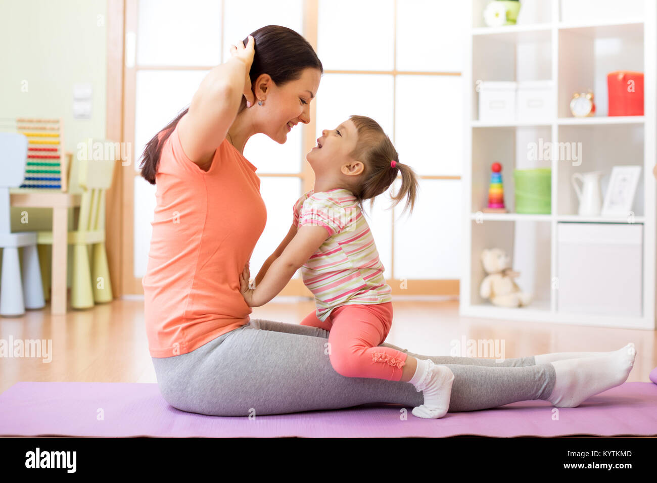 La mère et l'enfant tout-petit engagés dans fitness, yoga, l'exercice à la maison Banque D'Images