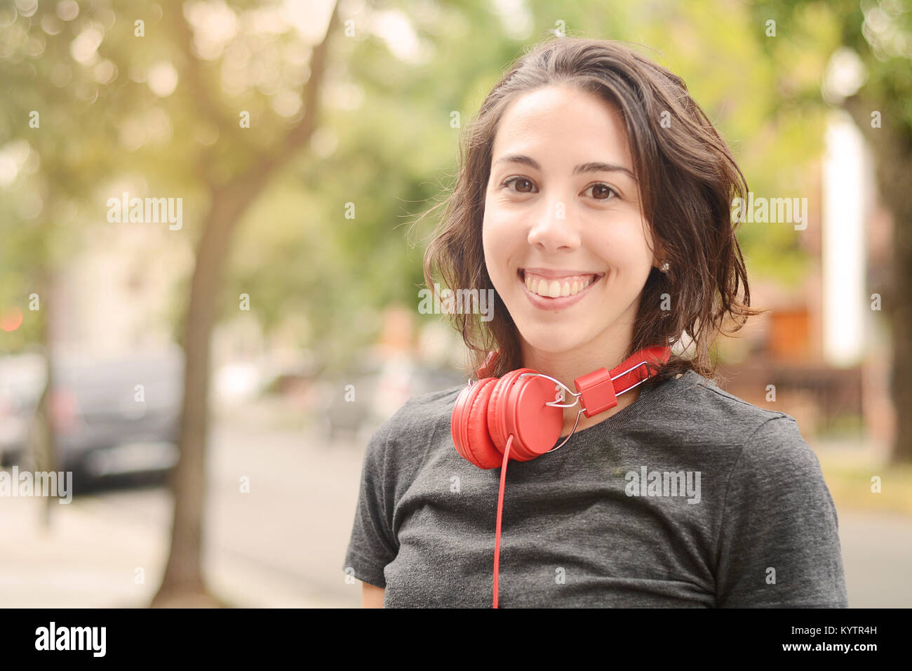 Portrait of young Beautiful woman with red headphones listening music. L'accent sur le casque. À l'extérieur. Concept urbain. Banque D'Images