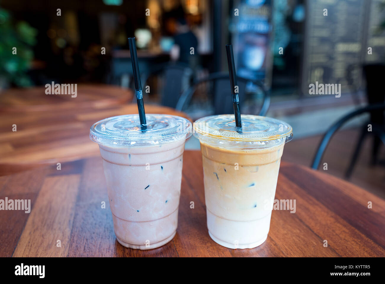 Moka glacé et des boissons au café Latte glacé dans des verres en plastique avec paille sur une table en bois à l'extérieur d'un café. Banque D'Images