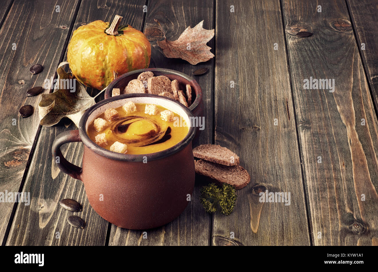 Soupe de potiron savoureux dans old enamel mug sur la table en bois rustique. La soupe est servie avec des croûtons et de l'huile de citrouille. Cette image est tonique. Banque D'Images