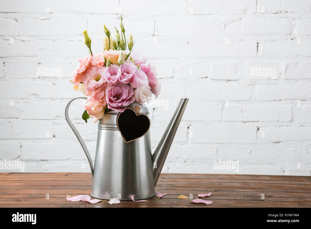 Vue rapprochée de belles fleurs en arrosoir avec symbole coeur vierge sur la surface en bois Banque D'Images