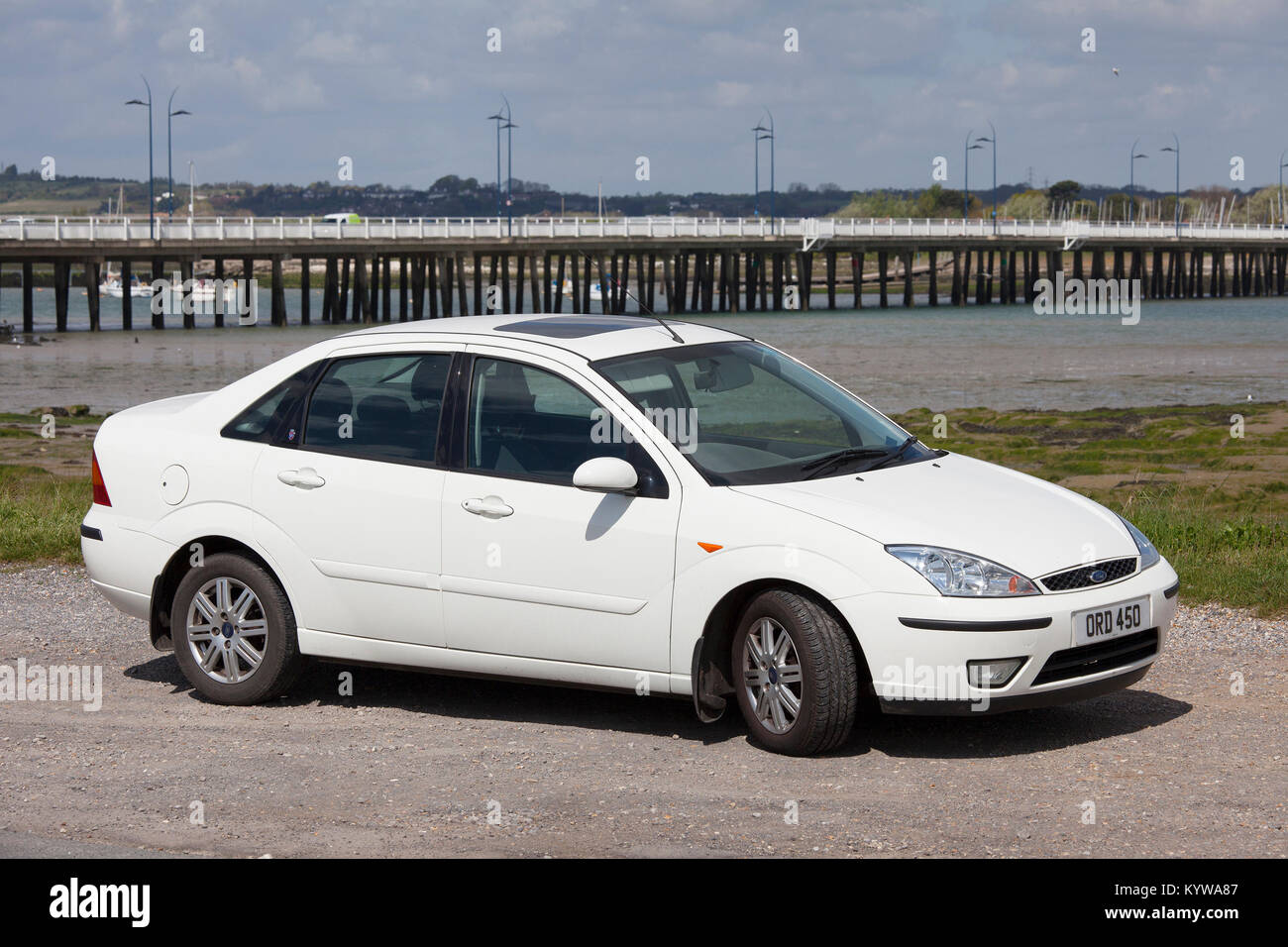 Un livre blanc 2004 Ford Focus 1.6 Ghia saloon, stationné à Hayling Island Bridge en arrière-plan Banque D'Images