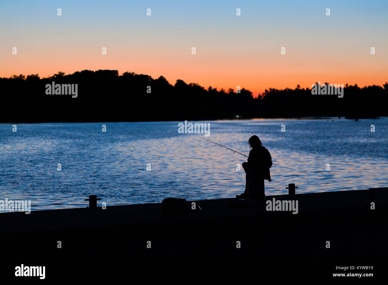 La silhouette d'une fille sur un quai de pêche au coucher du soleil à Port Severn, en Ontario, Canada. Banque D'Images