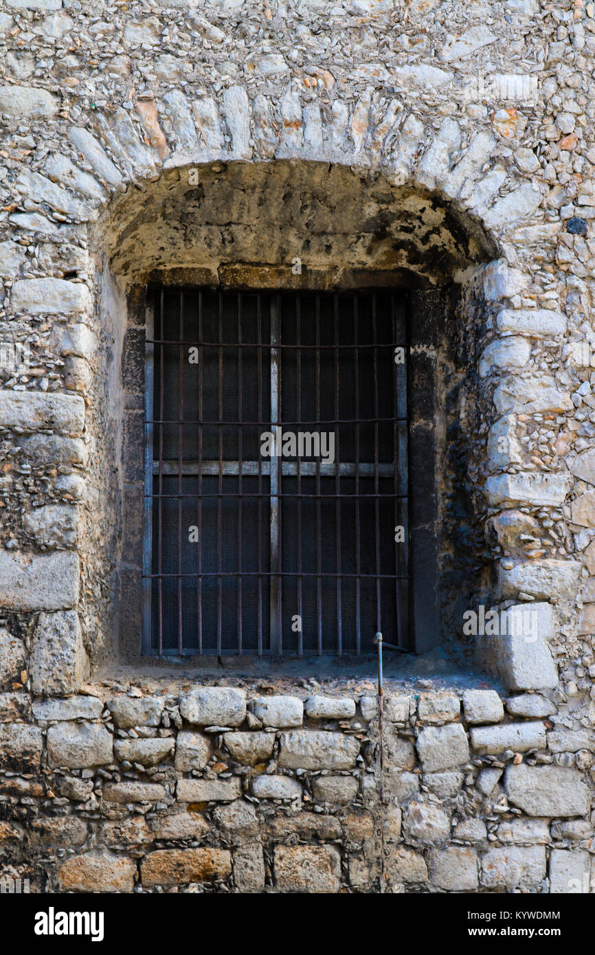 Fenêtre cintrée avec bars situé dans un mur de pierre rustique profonde Banque D'Images