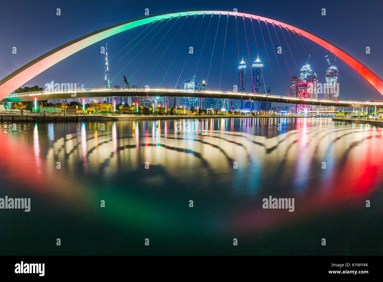 Amazing Dubai skyline at night. Pont avec drapeau émirats couleurs sur elle. Réflexion sur l'eau colorée. Le développement, le progrès, la réussite de Dubaï. Monument Banque D'Images