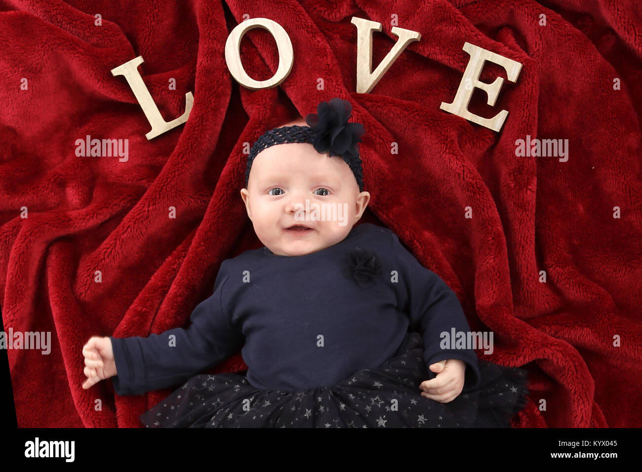 5 Mois Avec Bebe Fille En Robe Noire Se Detendre Sur Une Couverture Rouge Photo Stock Alamy