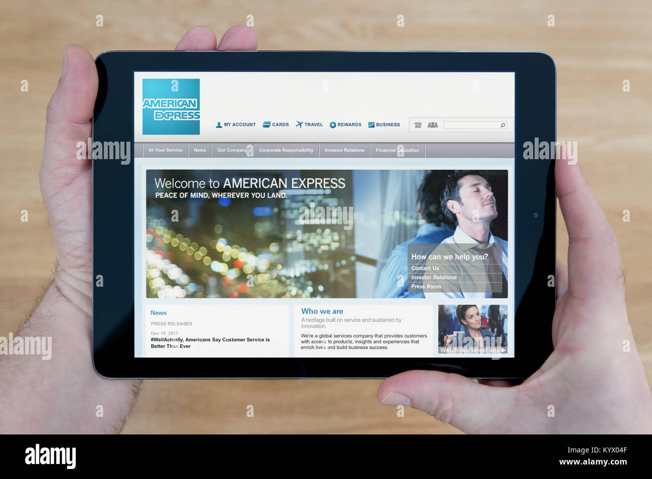 Un homme regarde le site d'American Express sur son iPad tablet device, avec une table en bois page contexte (usage éditorial uniquement) Banque D'Images