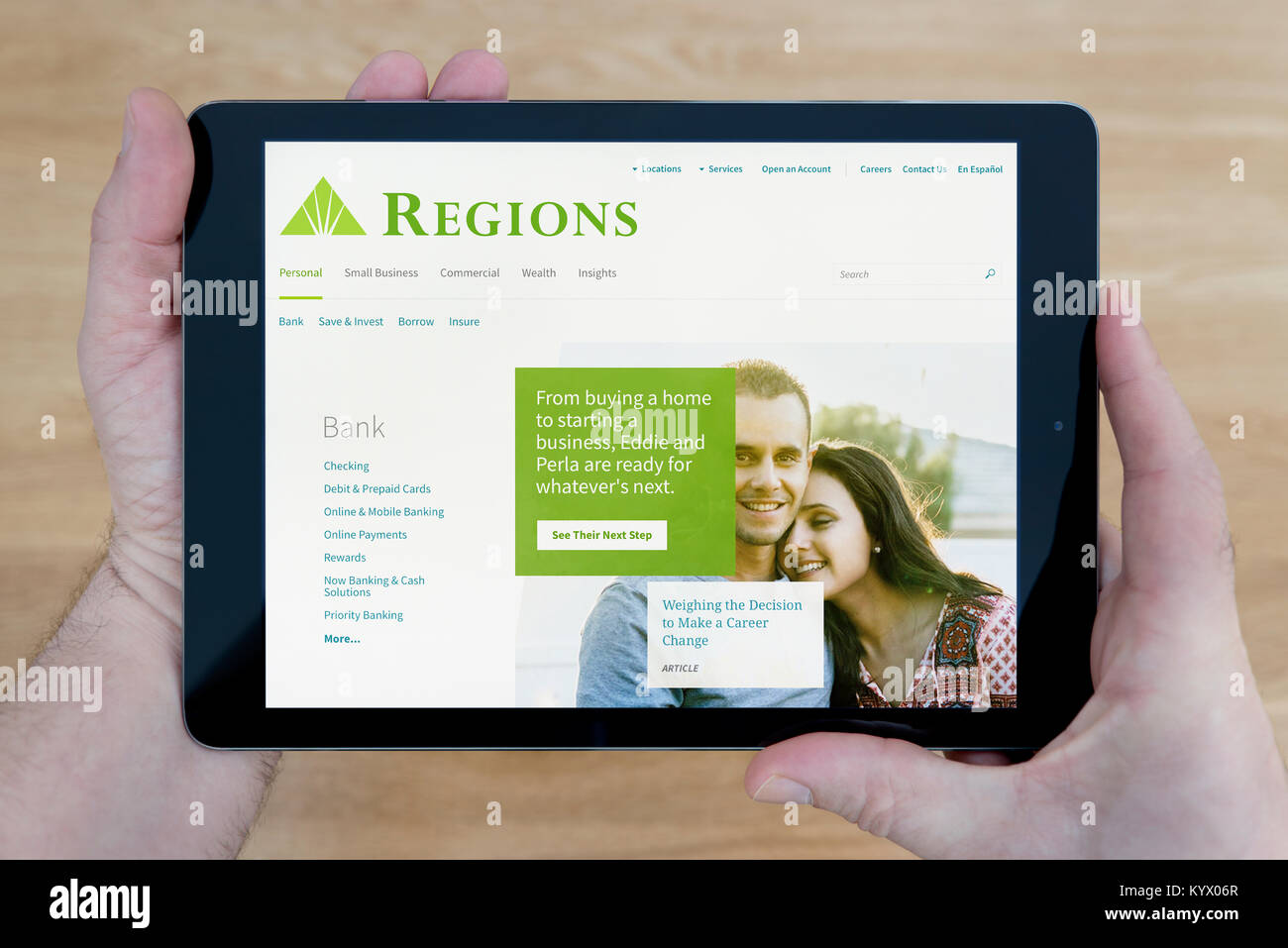 Un homme regarde les régions Financial Corporation site sur son iPad tablet device, avec une table en bois page contexte (usage éditorial uniquement) Banque D'Images