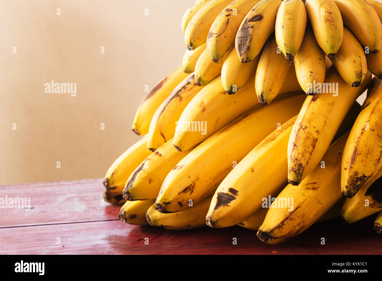 Grappe de Cavendish et mini bananes sur une table en bois rouge Banque D'Images