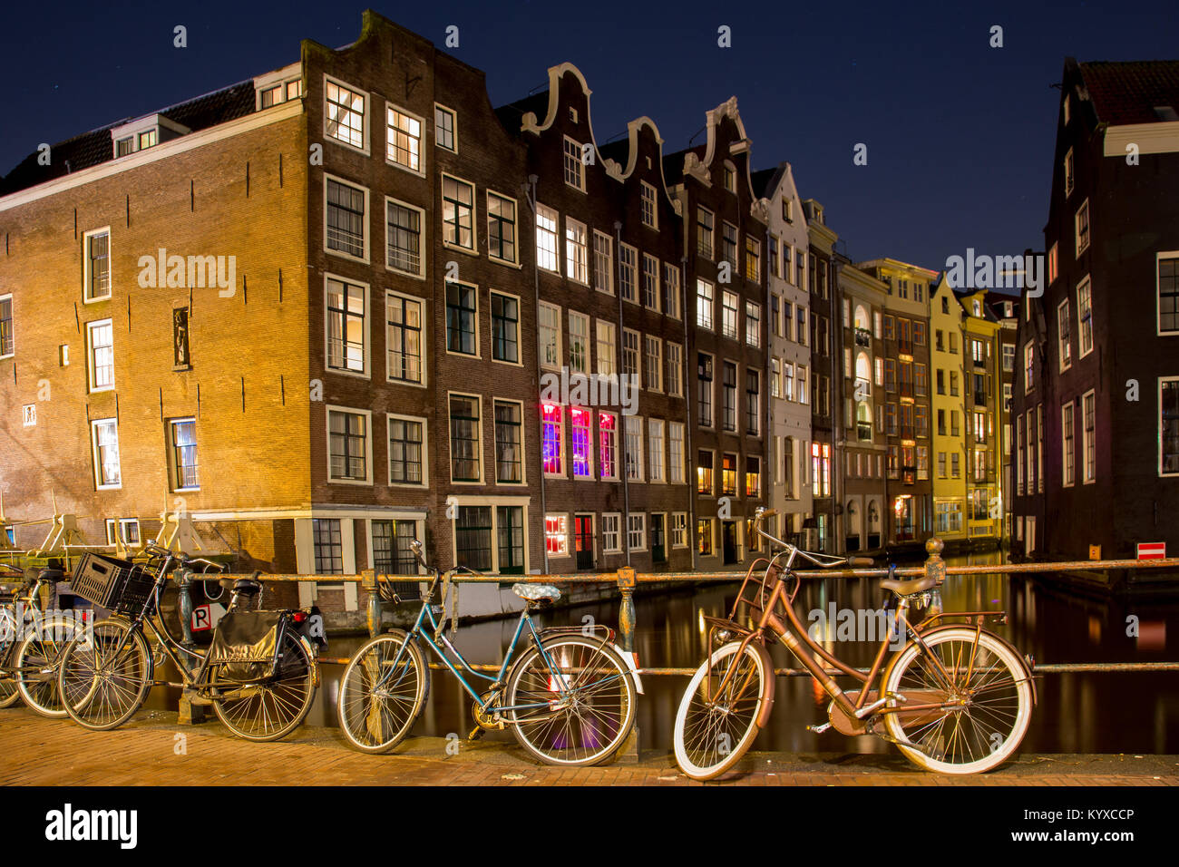 Les vélos d'Amsterdam garé près du canal et des maisons historiques de nuit Banque D'Images