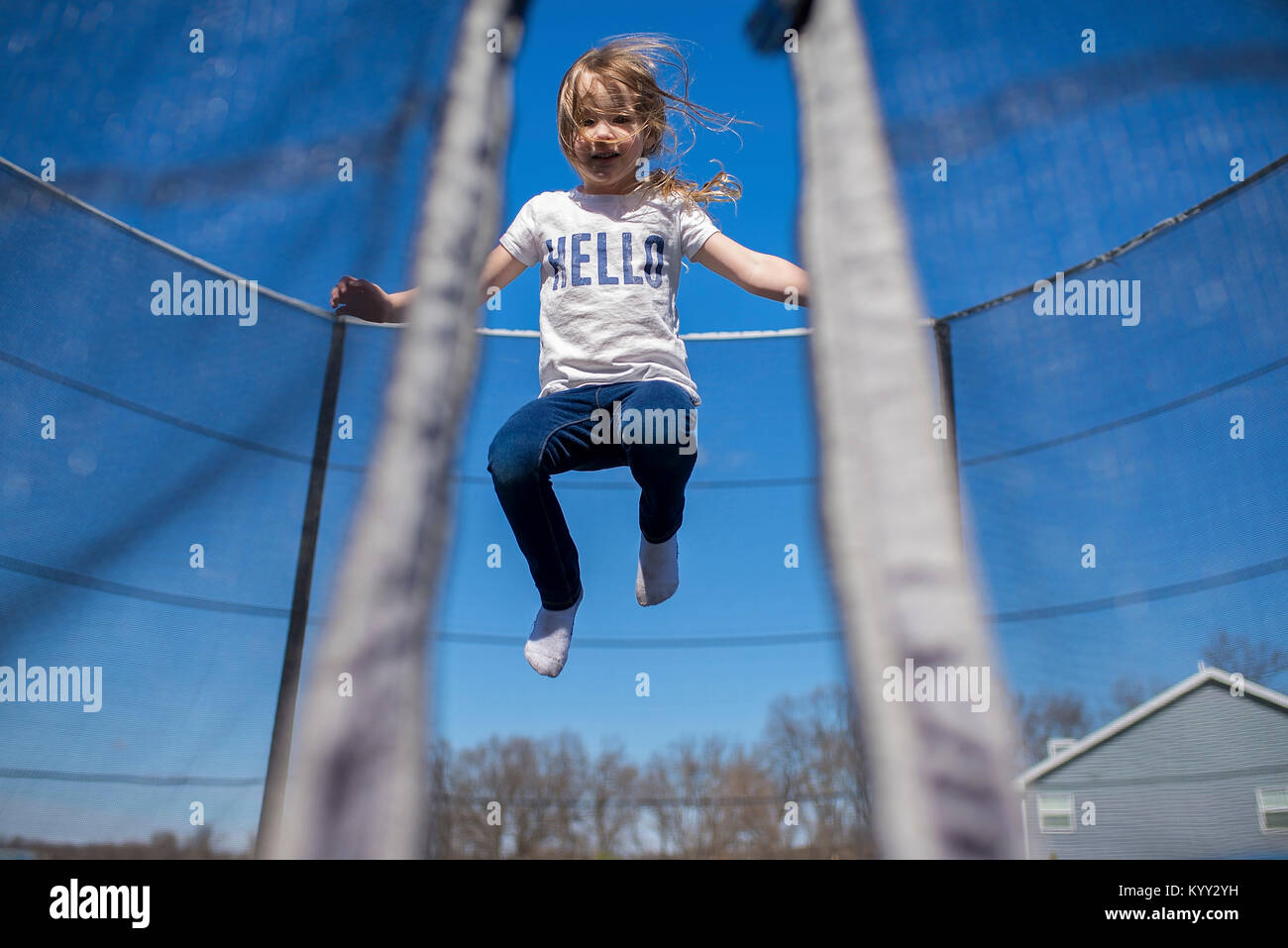Low angle view of girl playing on trampoline contre le ciel bleu Banque D'Images