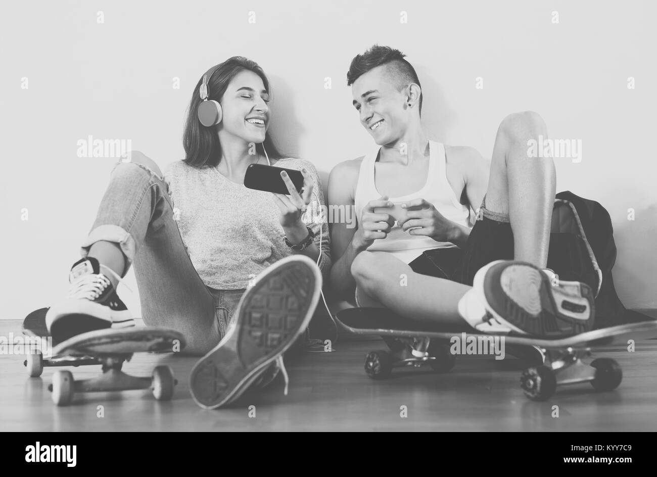 Fille et garçon adolescents jouant à des jeux en ligne sur smarthphones en intérieur domestique Banque D'Images