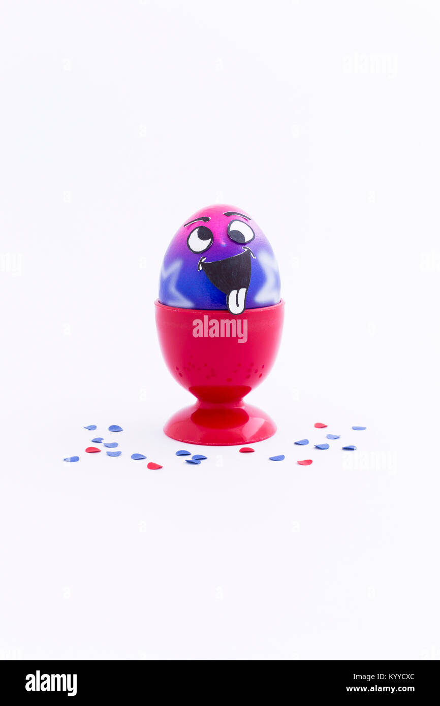 Peint en rose et pourpre avec des œufs de Pâques style cartoon funny face dans un oeuf en plastique rouge tasse et confettis colorés sur fond blanc Banque D'Images