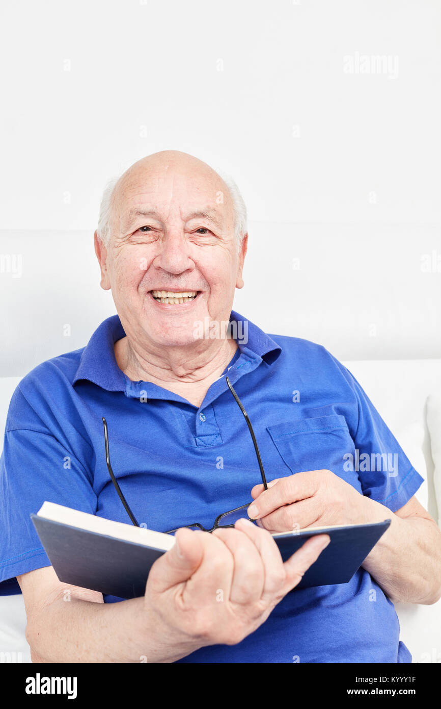 Happy senior en tant que pensionné lit un livre libre à maison de retraite Banque D'Images