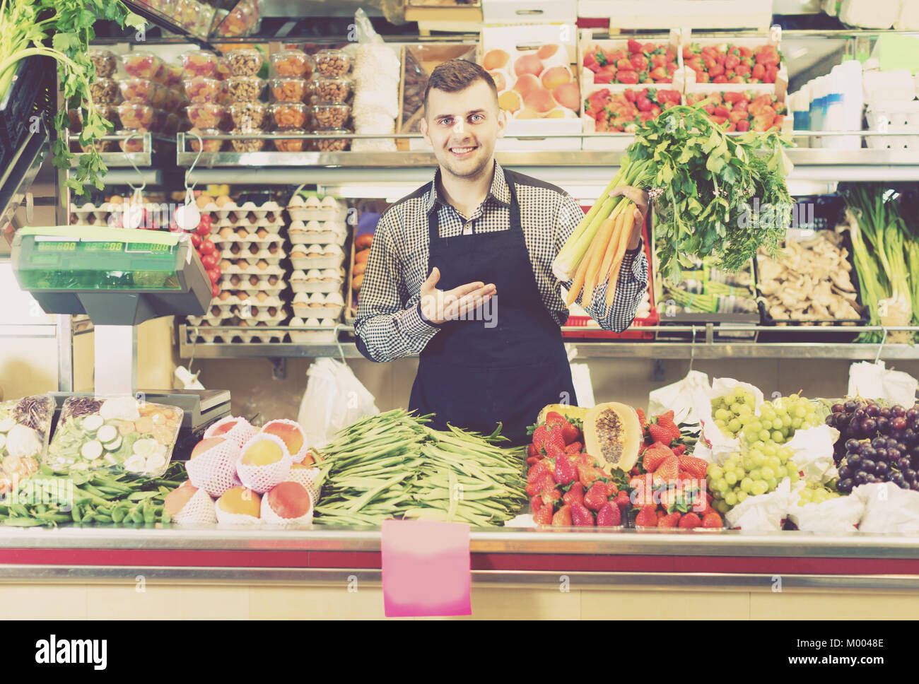 Vendeur homme 29 ans affiche assortiment d'épicerie. Banque D'Images