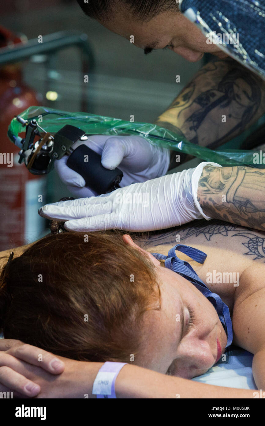 Tatoueur à l'œuvre à la Convention de tatouage dans le tabac Dock, London, England, United Kingdom Banque D'Images
