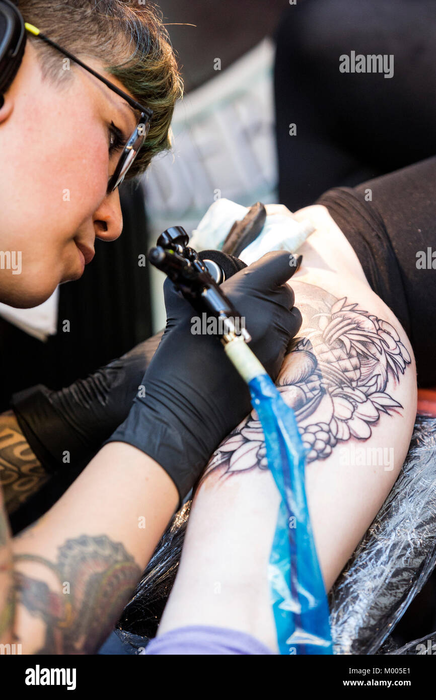 Tatoueur à l'œuvre à la Convention de tatouage dans le tabac Dock, London, England, United Kingdom Banque D'Images