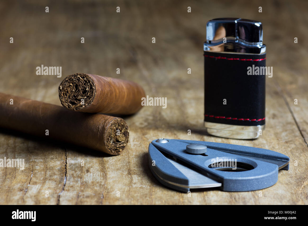 Deux cigares cubains avec un briquet et un couteau sur une vieille table en bois Banque D'Images