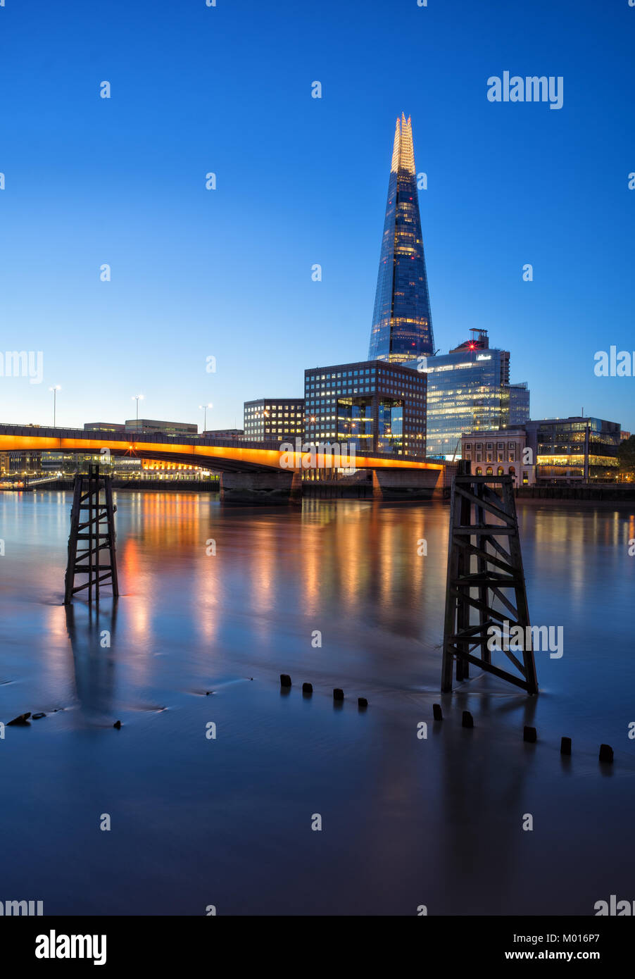 Le Shard s'élève dans le bleu profond du crépuscule tandis que les lumières chaudes du pont scintillent à travers la Tamise. Banque D'Images