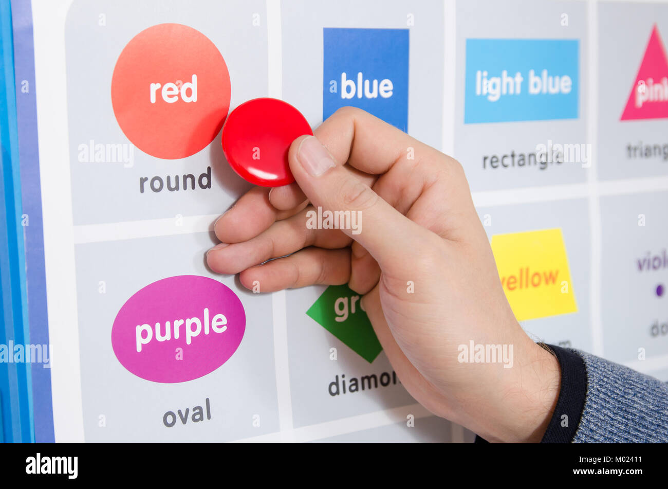 Un éducateur masculin explique l'orthographe du mot rouge sur la table de la formation en salle Banque D'Images