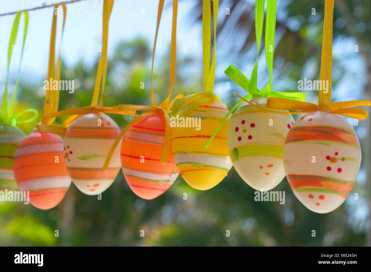 Décoration de Pâques, les oeufs de Pâques colorés accrochés sur une corde dans un jardin tropical. Banque D'Images