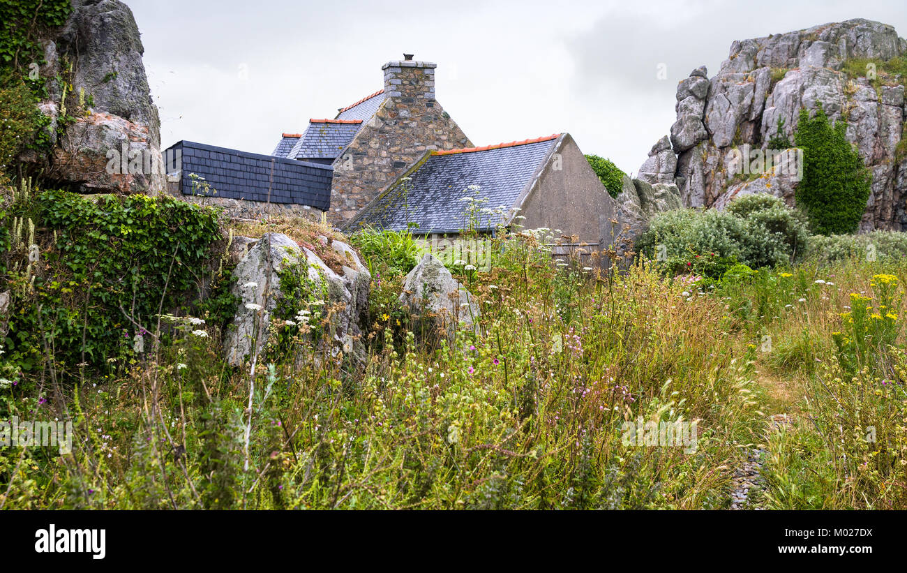 Voyage en France - maison en pierre typiquement breton et rochers à Plougrescant ville des Côtes-d'Armor en Bretagne au jour d'été pluvieux Banque D'Images