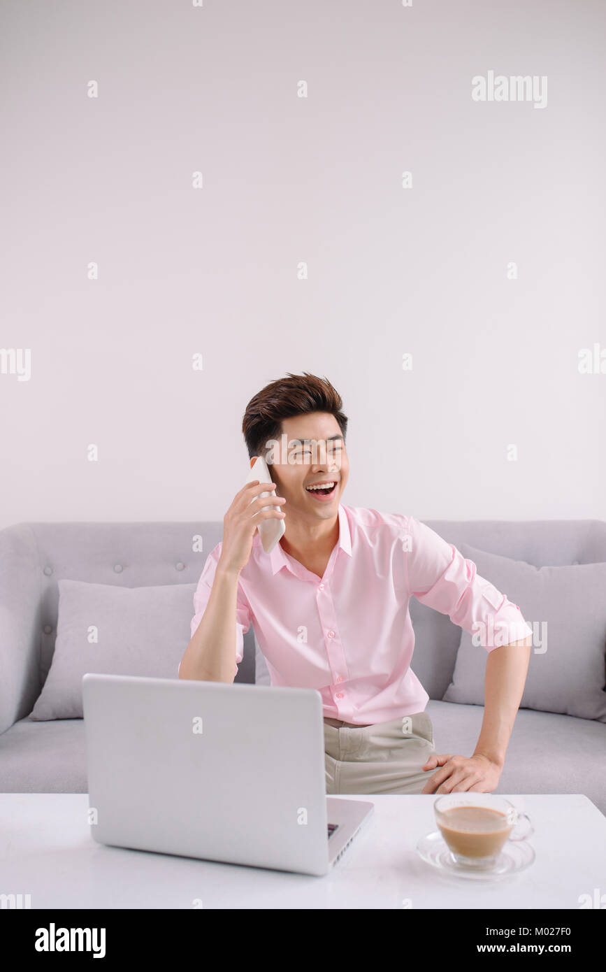 Beau jeune homme asiatique avec un ordinateur portable sur le téléphone Banque D'Images
