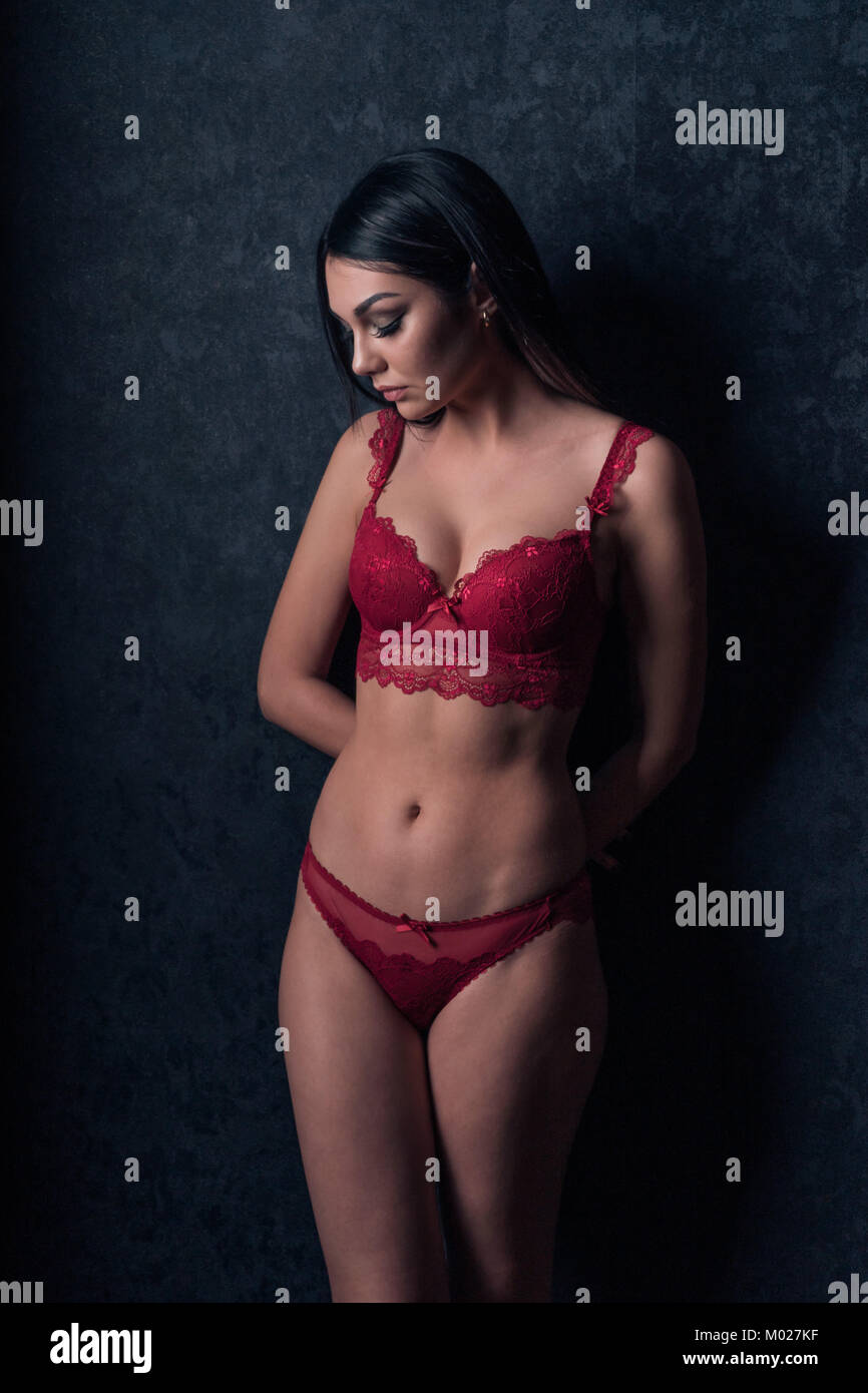 Fille sexy en lingerie rouge debout près du mur Banque D'Images
