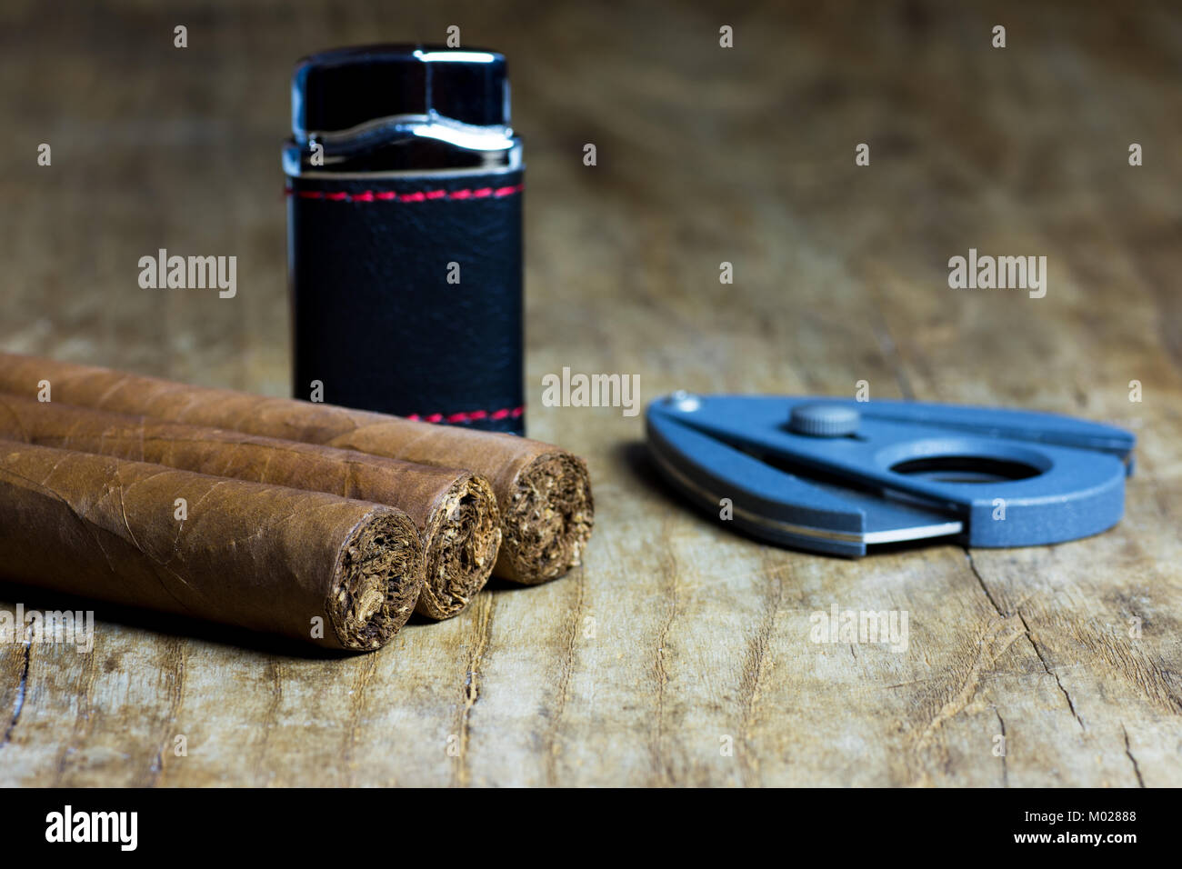 Trois cigares cubains avec un briquet et un couteau sur une vieille table en bois Banque D'Images
