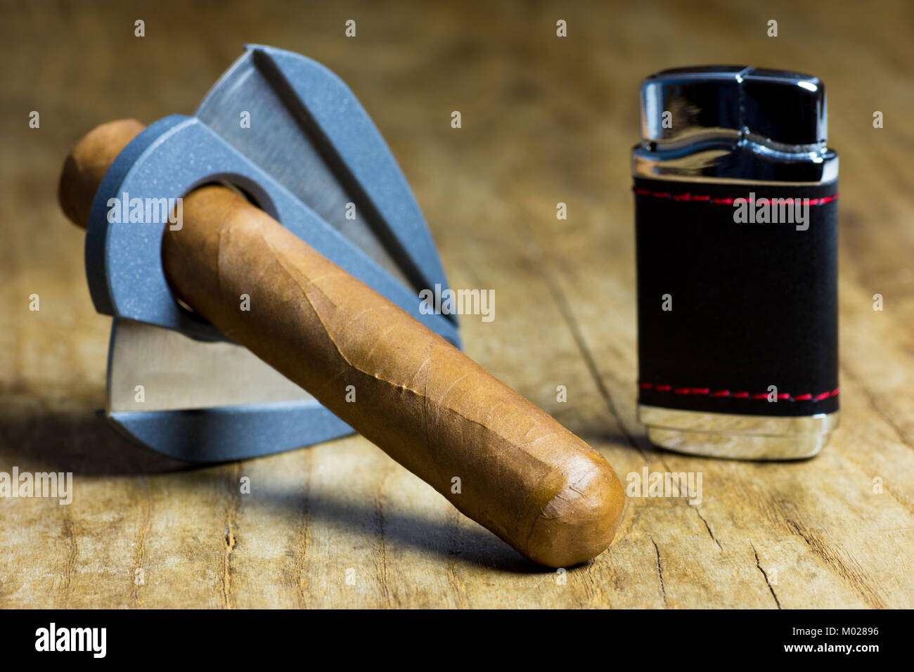 Cigare cubain avec un briquet et un couteau sur une vieille table en bois Banque D'Images