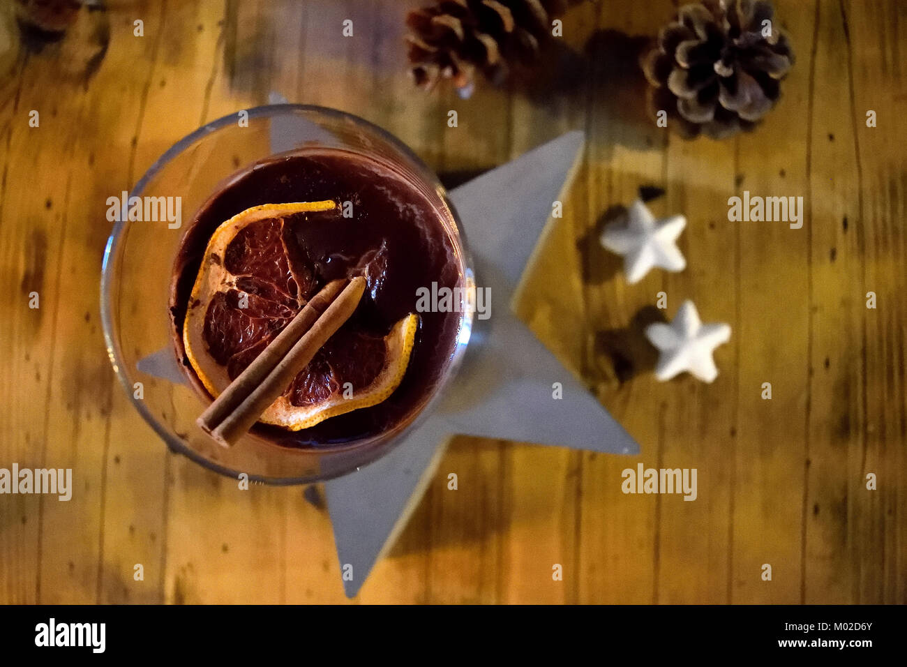 Un verre de chocolat chaud vu de dessus avec la cannelle et d'une tranche d'orange contre une table en bois, étoile et des pommes de pin Banque D'Images