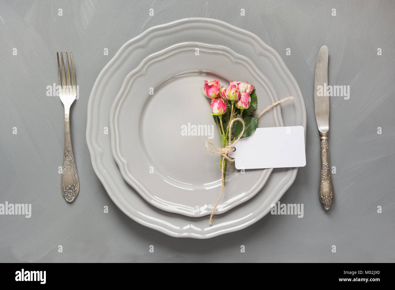 Table de fête avec des fleurs, de la vaisselle vintage, l'argenterie et les décorations sur fond gris. Vue d'en haut. Concept. Banque D'Images