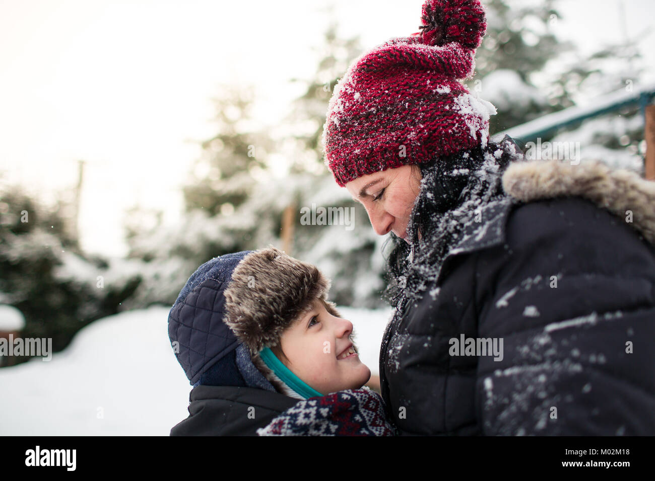 Vue latérale d'une heureuse mère et son fils se regarder dans les yeux après une bataille de boules de neige Banque D'Images