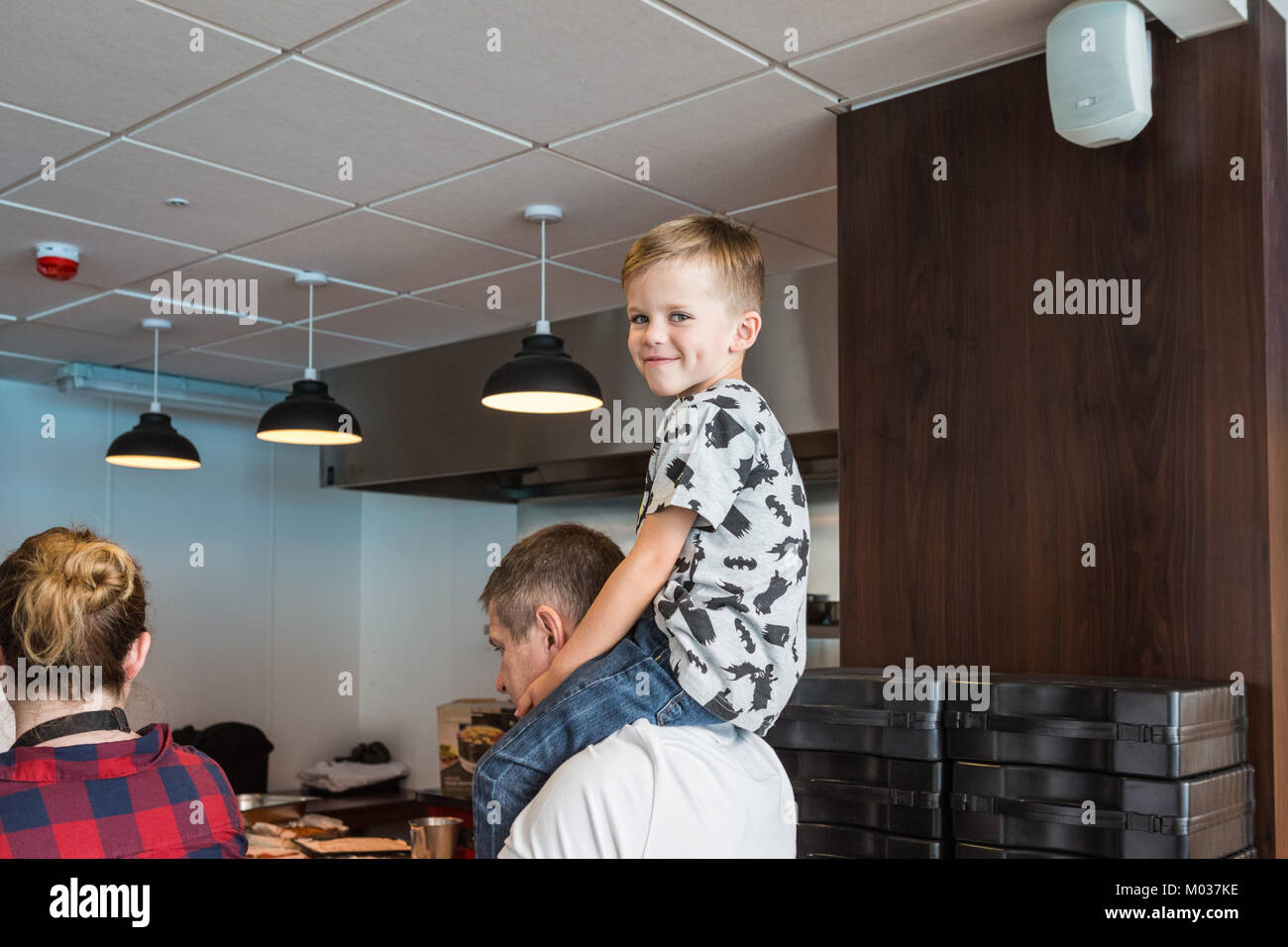 Jeune garçon assis sur les épaules des pères au cours de démonstration de cuisine Banque D'Images