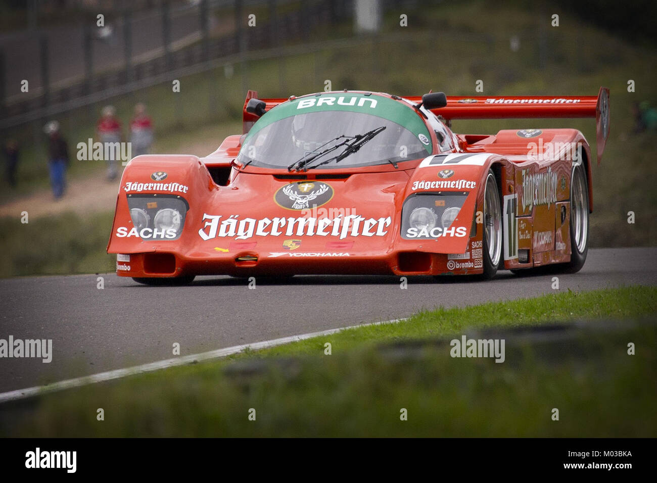 La Porsche 962C Brun Jagermeister est une voiture de course conçue pour les courses d'endurance. Sa livrée orange et noire distinctive est devenue emblématique dans le monde des sports mécaniques. Banque D'Images