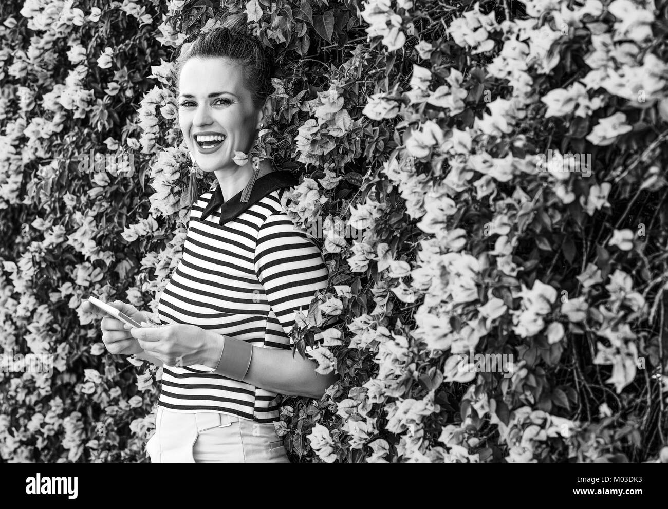 Fraîcheur colorée. smiling woman in élégante Chemise à rayures à l'avant du lit coloré fleurs magenta écrit sms Banque D'Images