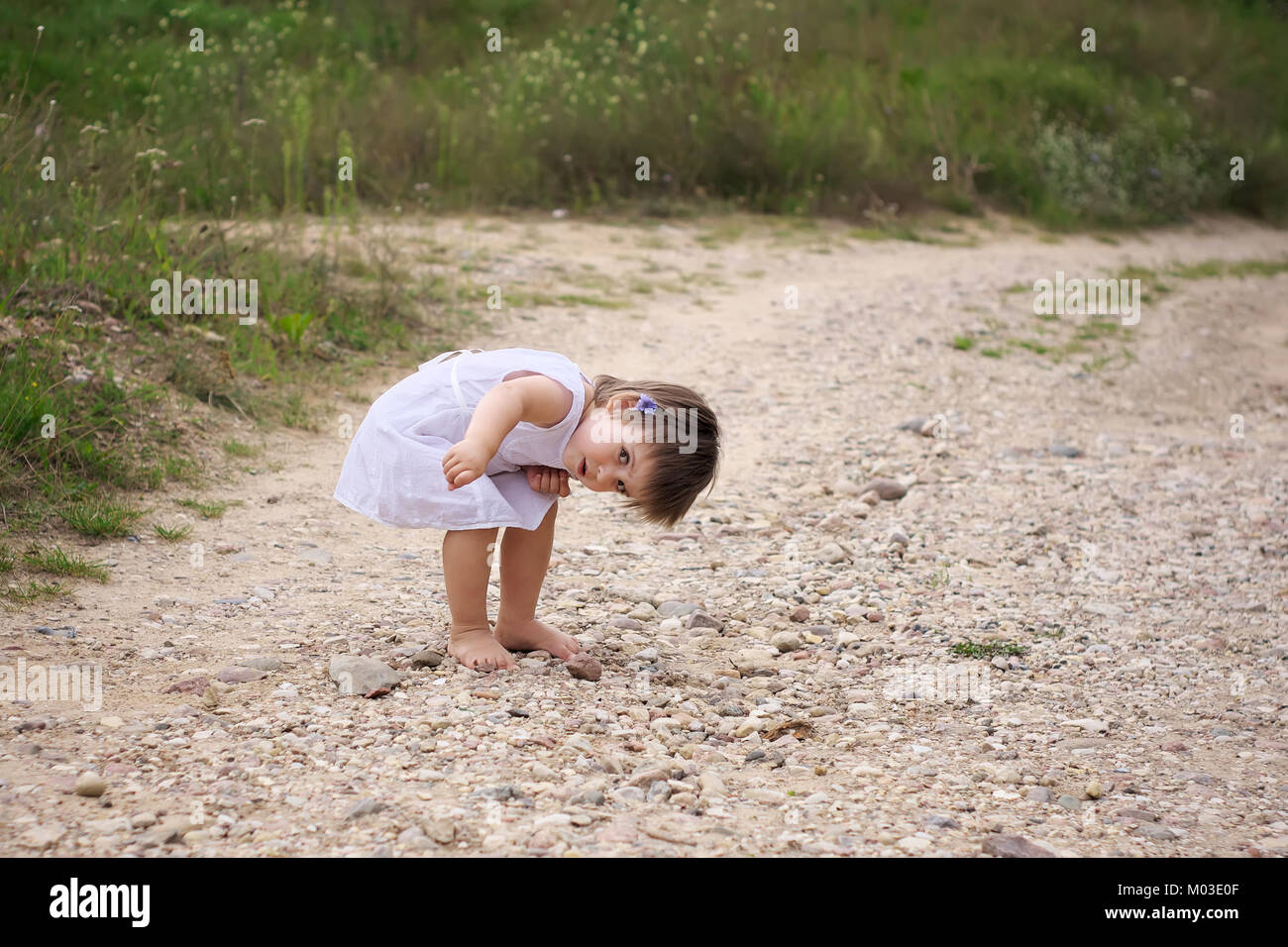Petite fille a trouvé des débris sur la route robe blanche et rouge sable  sandales road Photo Stock - Alamy