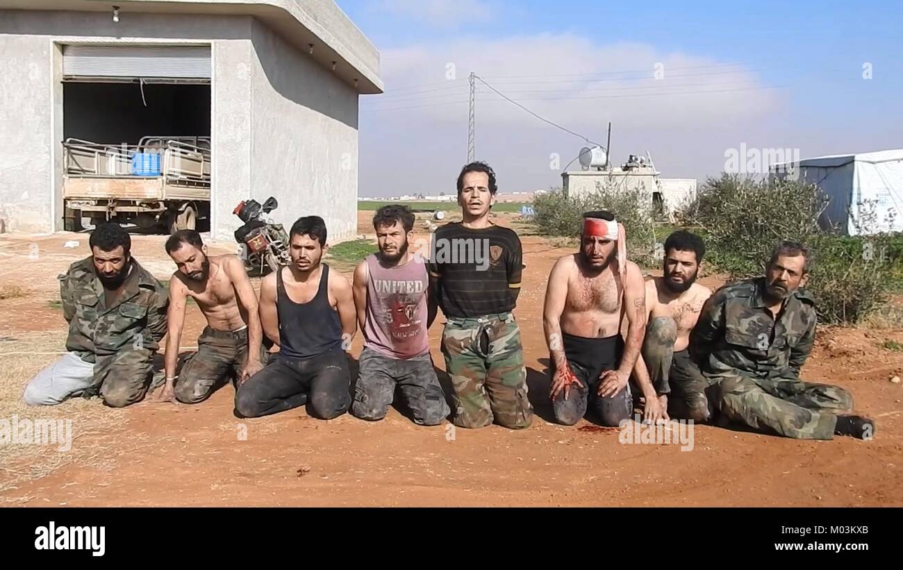 Toujours image réalisée à partir d'une vidéo de propagande publié le 14 janvier 2018 montrant des soldats de l'armée syrienne prisonniers d'État islamique près de combattants dans la base aérienne Abu Duhur Le Gouvernorat d'Idlib, en Syrie. Banque D'Images