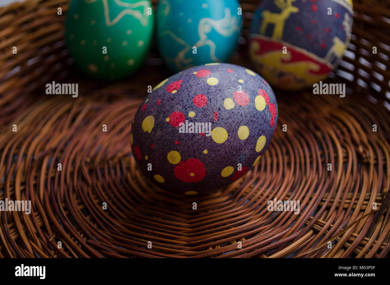 Les oeufs de Pâques peints colorés dans un panier en paille Banque D'Images