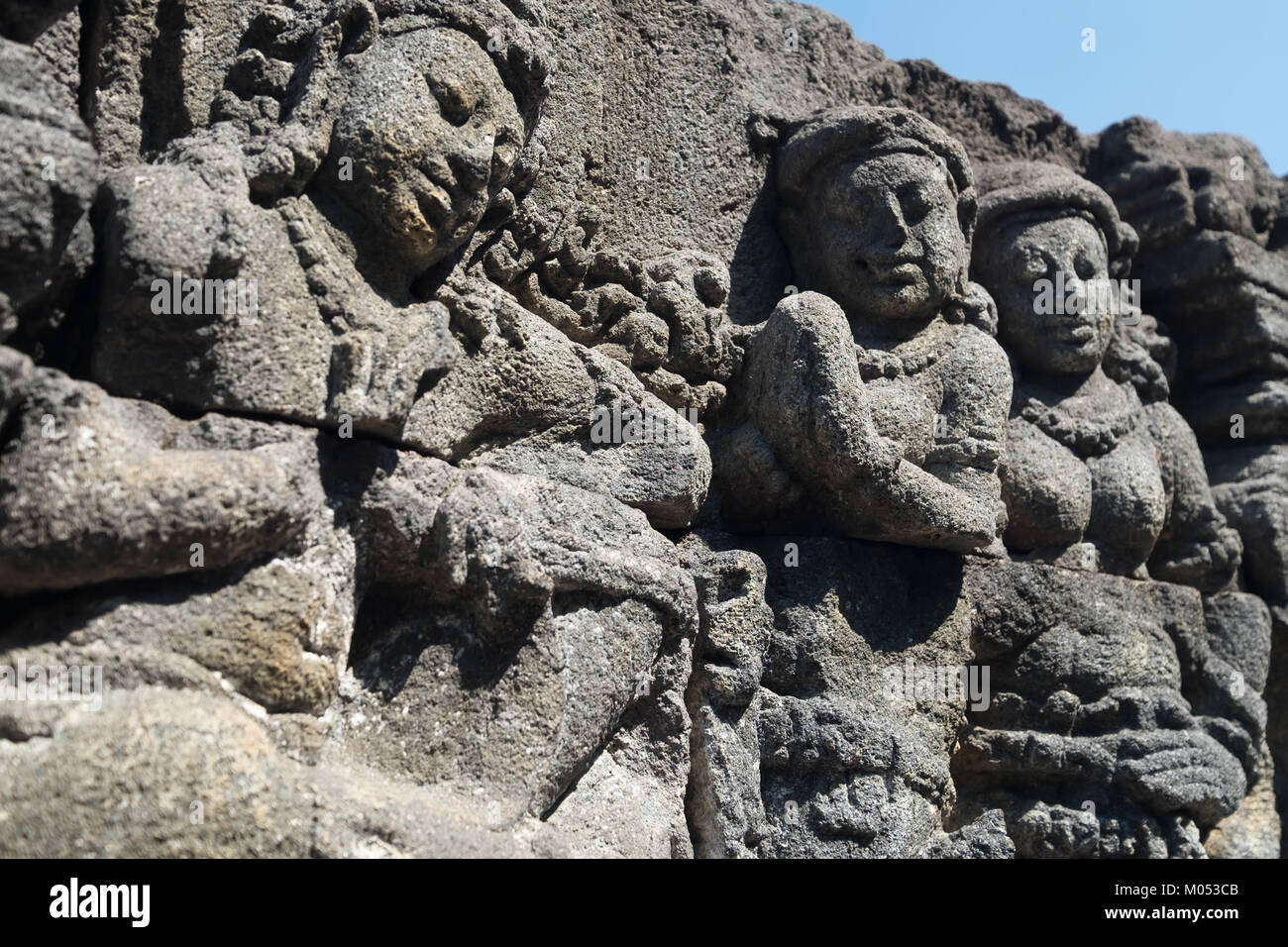 Mur libre ornée de bas-reliefs représentant des scènes de la vie de l'ancienne Java et les visages. La sculpture sur pierre très détaillées. Bouddhiste de Borobudur Banque D'Images