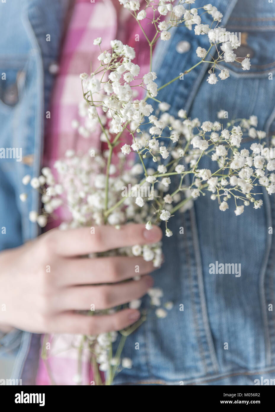Girl holding Baby's Breath fleurs délicates contre sa poitrine Banque D'Images