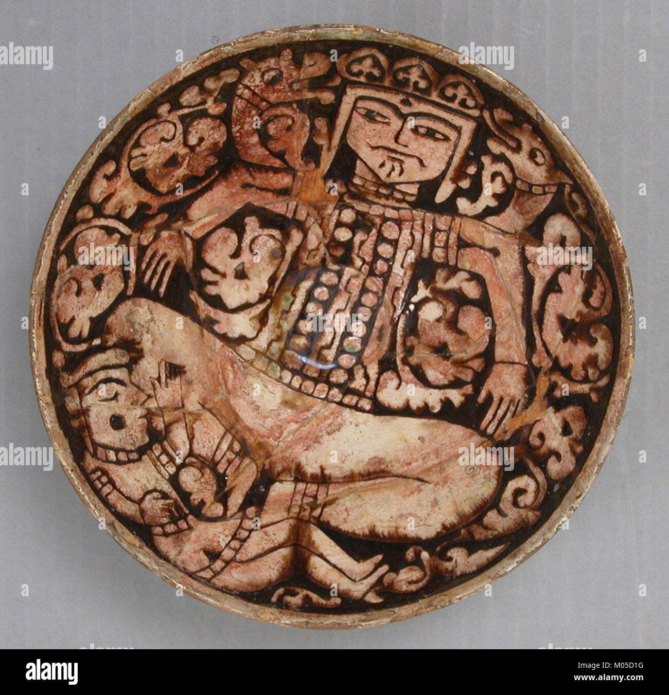 Un bol représentant le roi mythologique Zahhak, avec des serpents dépassant de ses épaules, un artefact important de l'art persan antique, mettant en valeur les thèmes mythologiques de la culture persane. Banque D'Images