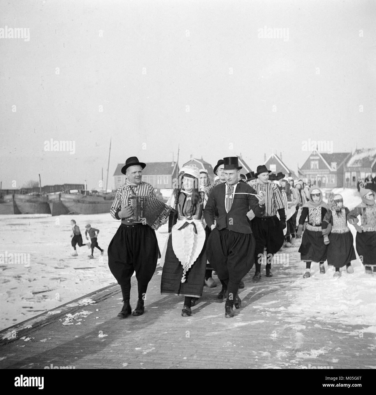 Une photographie représentant un couple marié en tenue traditionnelle néerlandaise, accompagné d'un ensemble musical, célébrant un cortège culturel de mariage dans les pays-Bas historiques. Banque D'Images