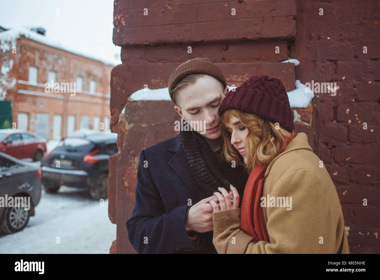 Young man and woman embracing près de brick coin de bâtiment. Rue d'hiver. La vie privée dans les endroits reculés de la grande ville Banque D'Images