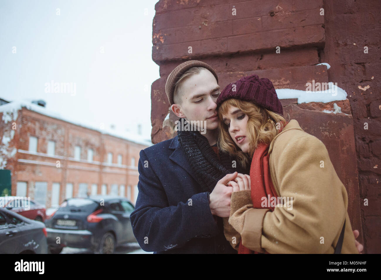 Young man and woman embracing près de brick coin de bâtiment. Rue d'hiver. La vie privée dans les endroits reculés de la grande ville Banque D'Images