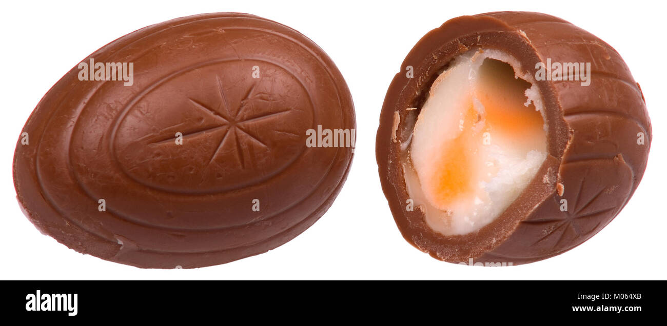 Cette image montre un œuf Cadbury Creme entier et fendu, un chocolat populaire de saison connu pour sa garniture crémeuse. Il met en évidence la structure et l'emballage de la friandise, qui est largement consommée pendant Pâques. Banque D'Images