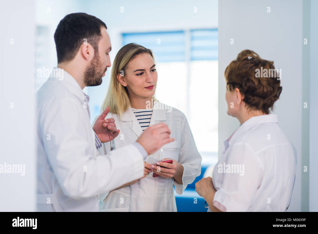 Mature doctor discuter avec les infirmières dans un couloir l'hôpital. Discuter de l'état du patient médecin avec son personnel médical après l'opération. Banque D'Images