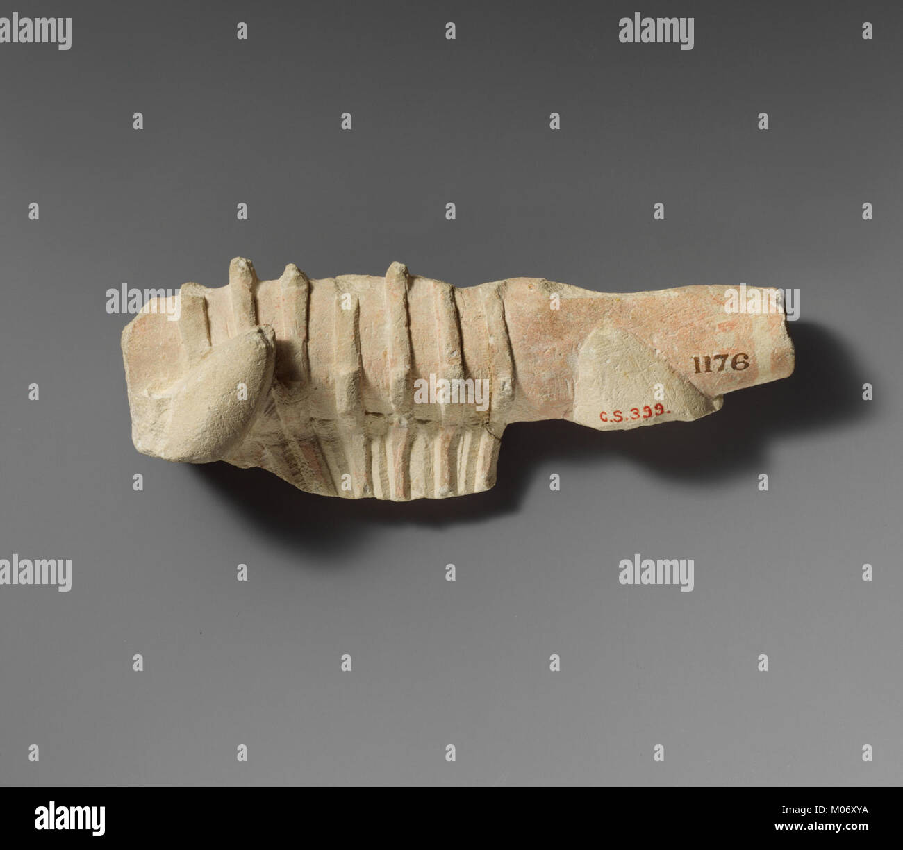 Ce fragment de calcaire représente une lyre, un ancien instrument à cordes, soulignant les détails de la sculpture et donnant un aperçu des pratiques musicales et artistiques du passé. Banque D'Images