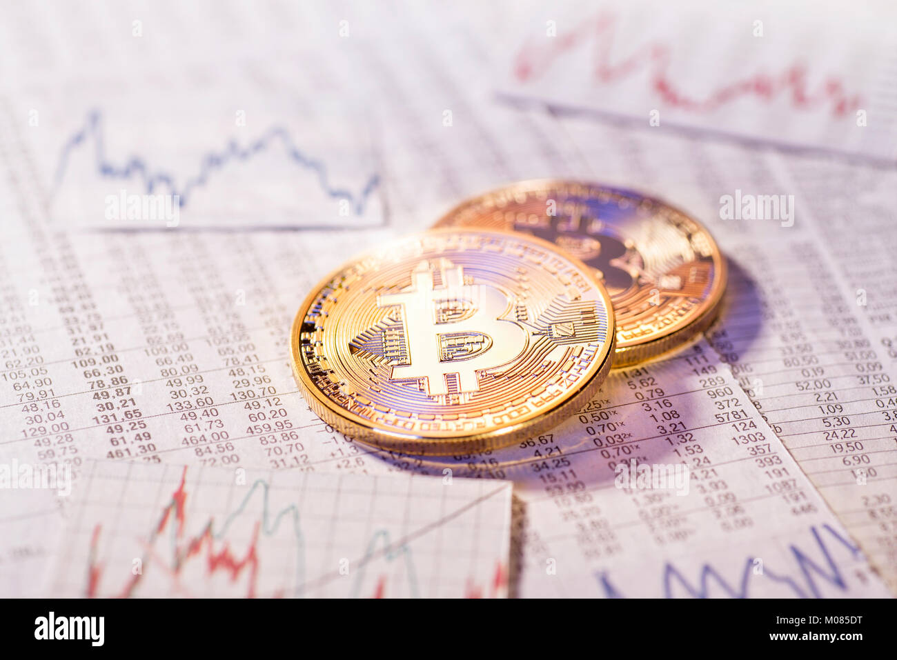 Deux pièces de monnaie Bitcoin avec tableaux et graphiques avec des taux de change Banque D'Images
