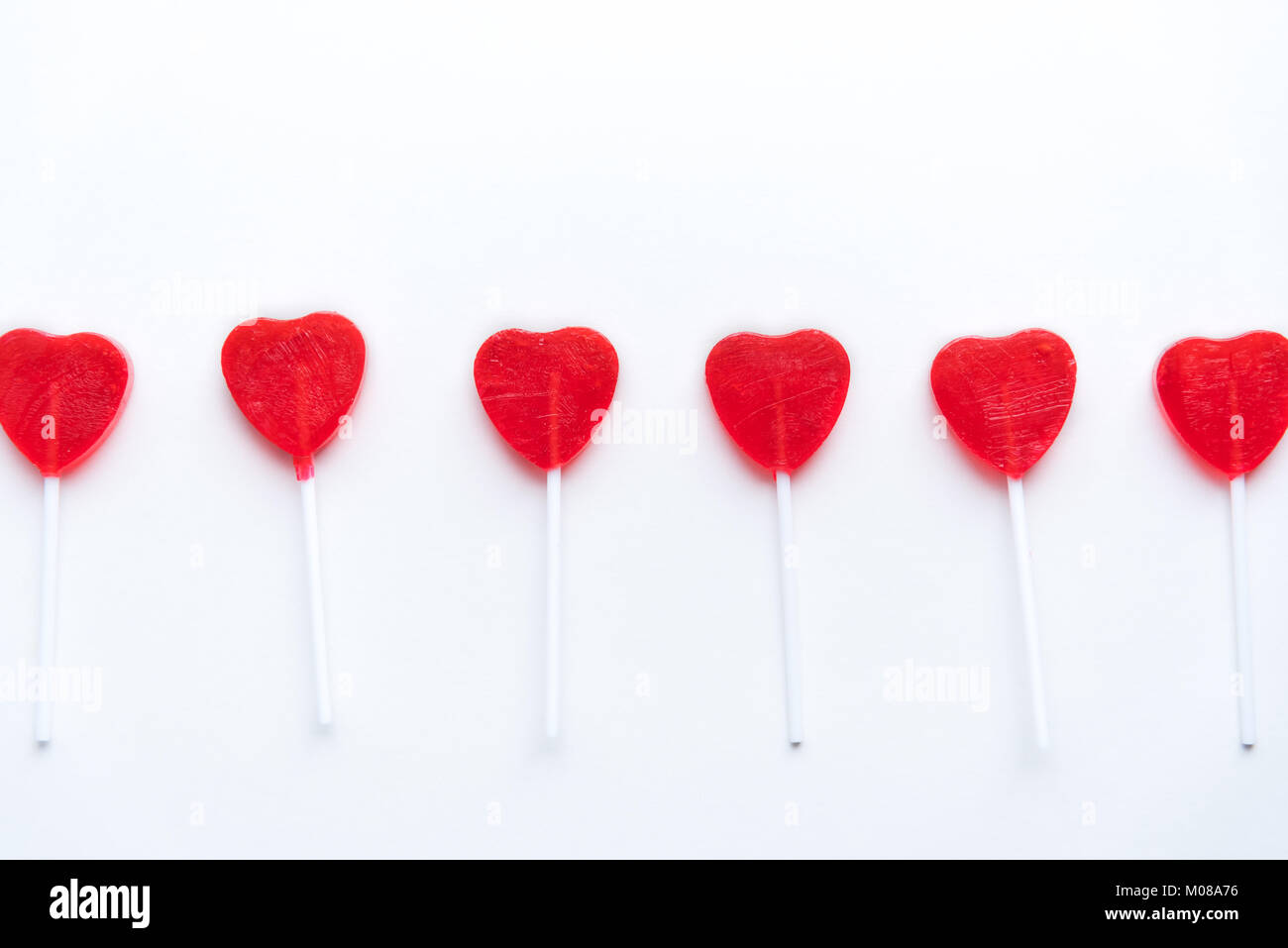 Saint Valentin coeur rouge lollipops dans une rangée sur fond blanc Banque D'Images